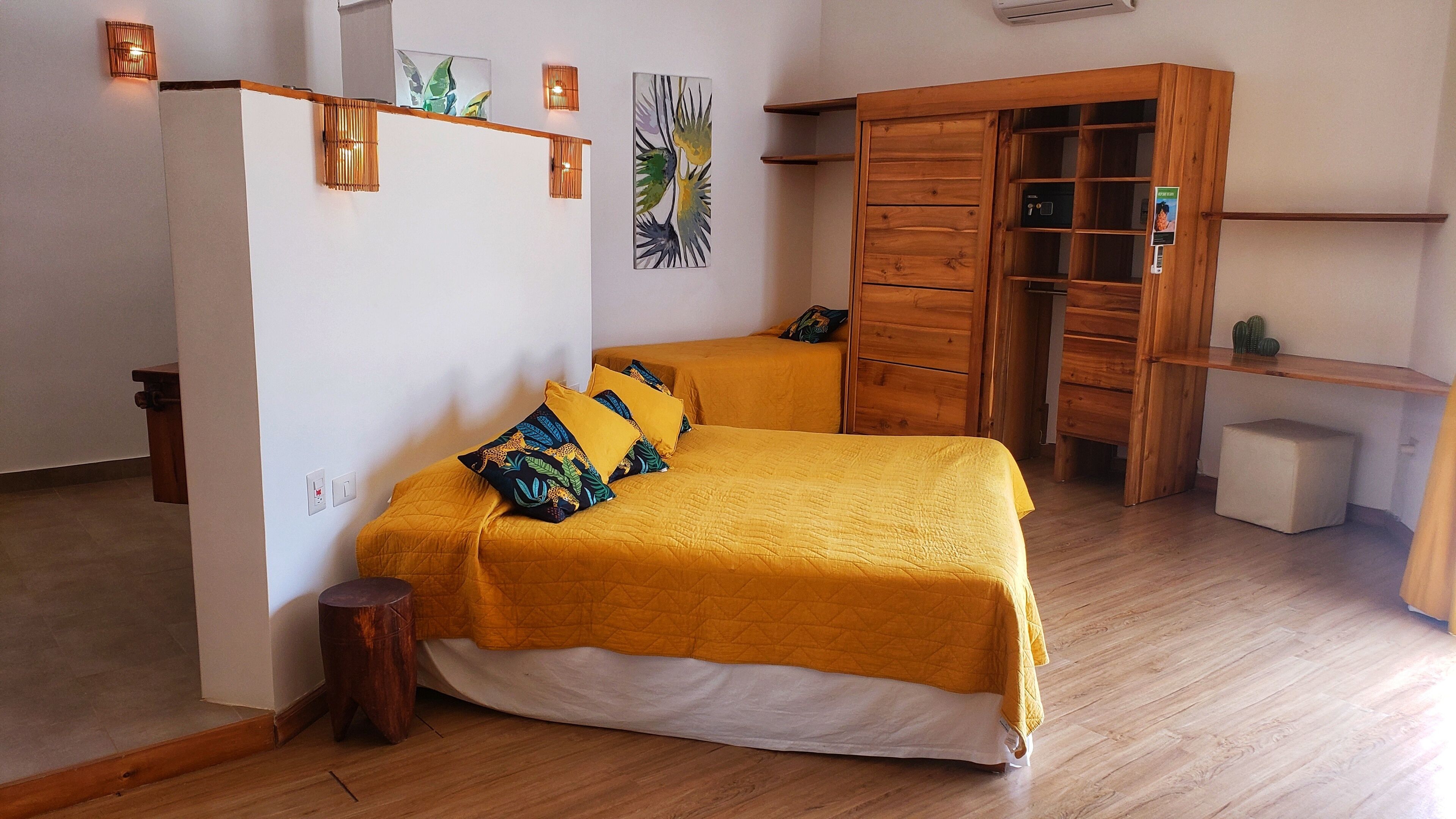 Een kamer met twee bedden, een houten garderobe en kunst aan de muur.