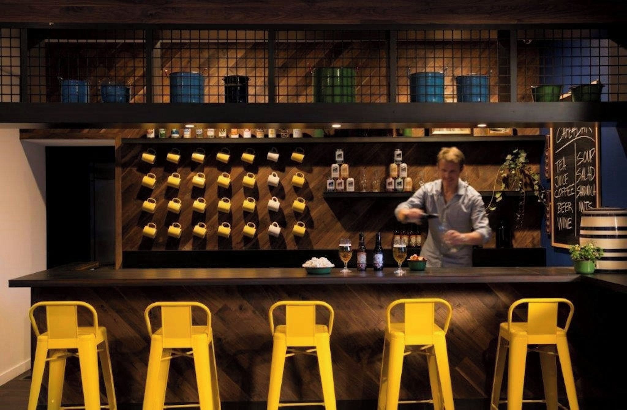 A bar area with a bartender, a wall of liquor bottles, and a chalkboard menu.