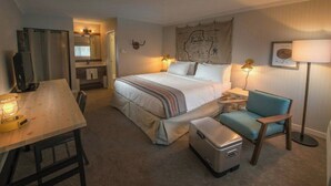 Une chambre d’hôtel avec un lit, une table de chevet, une chaise, un bureau et une valise.
