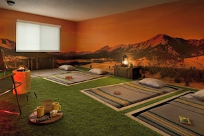 A room with four beds, a window, a wall mural, a small table with a tray, and a lamp. - Basecamp Boulder (Boulder)
