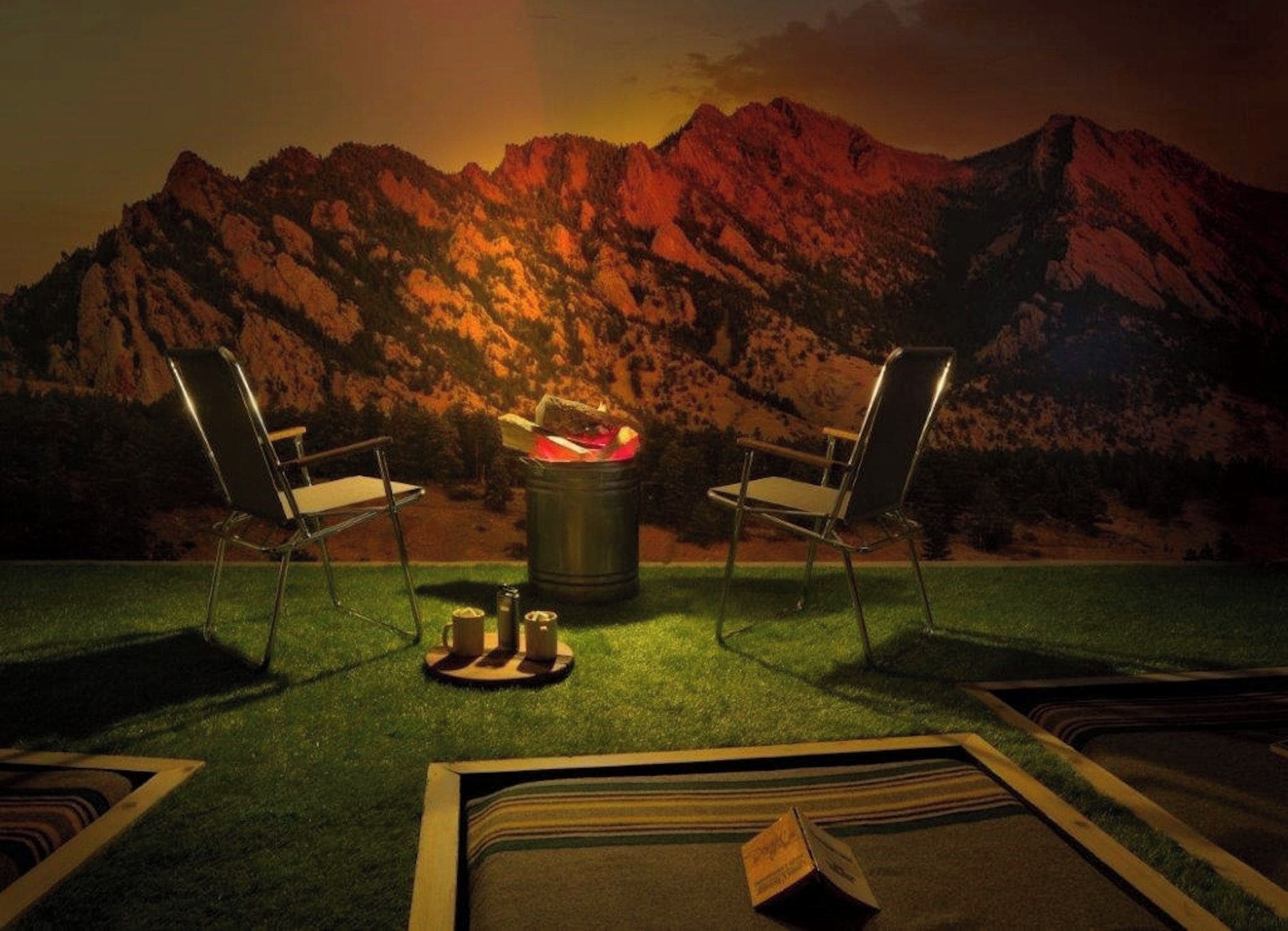 Two chairs facing a campfire with a mountainous backdrop.