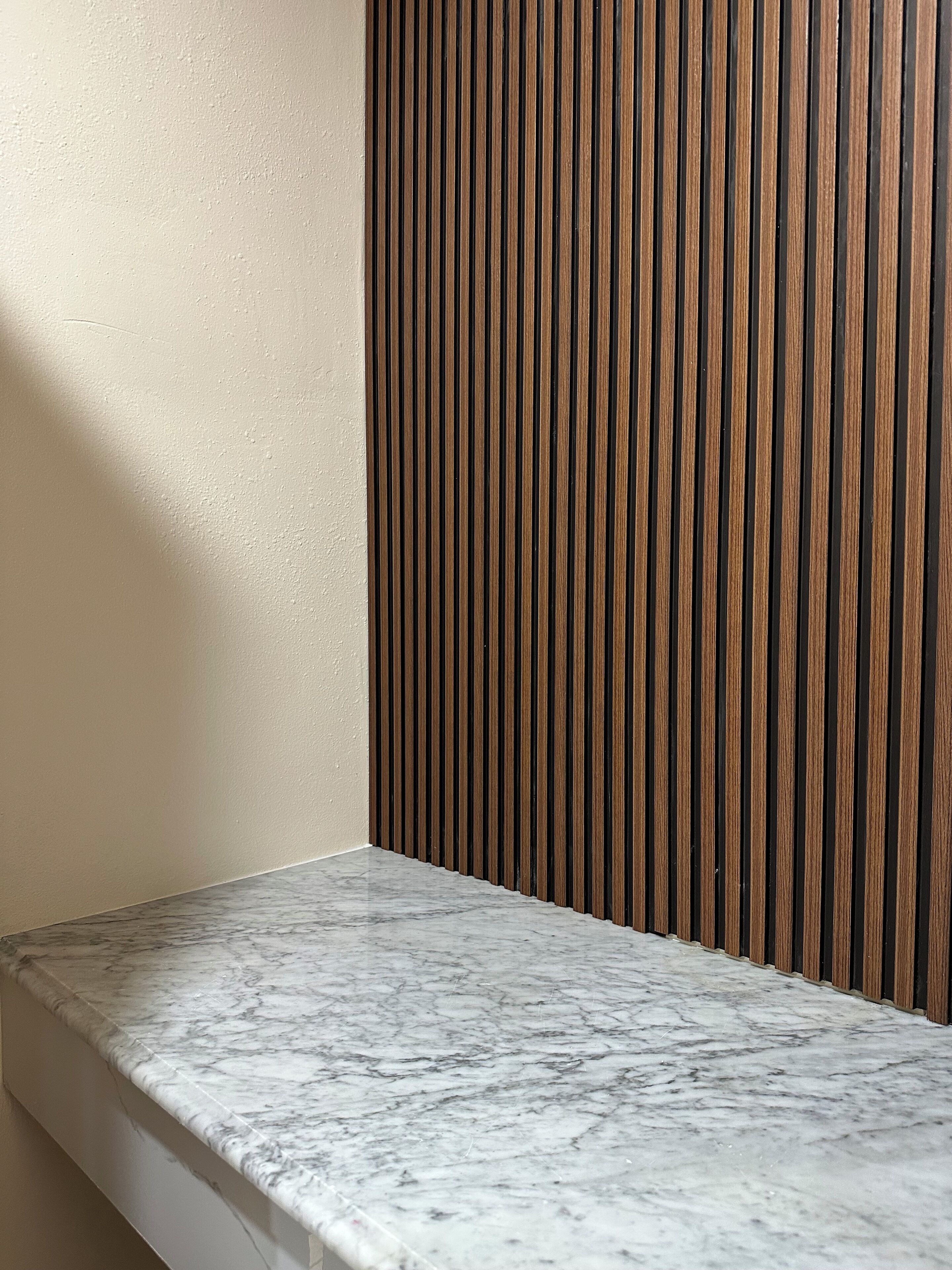 Un coin de pièce avec un comptoir en marbre et un mur recouvert de lambris en bois.