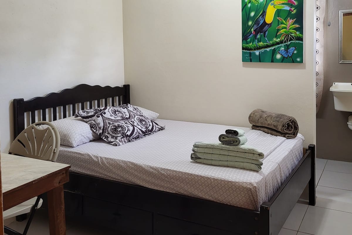 Une chambre à coucher avec un lit, une chaise, un bureau, un tableau et une salle de bain.