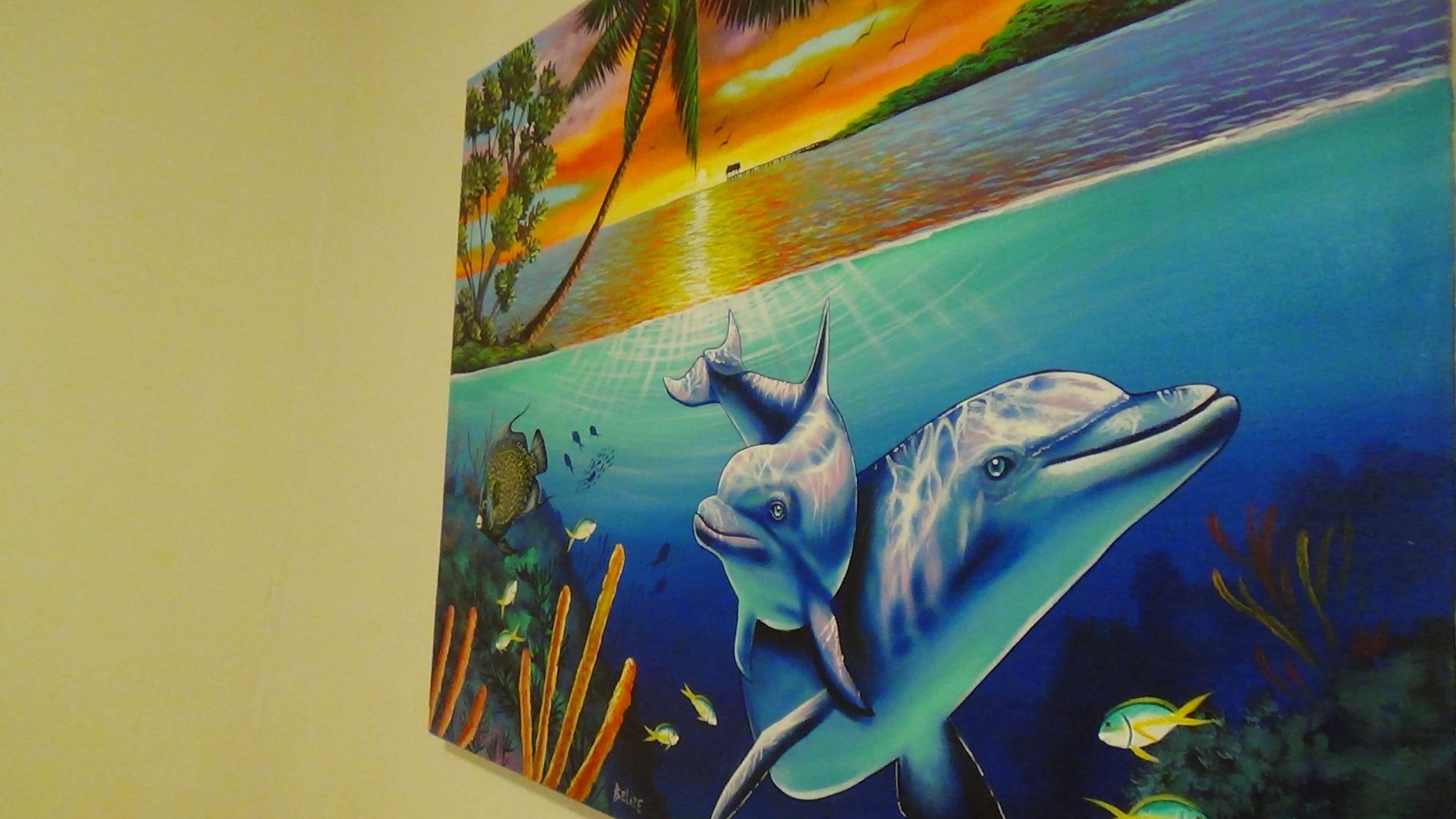 A wall mural depicting a dolphin and a sunset over a beach.