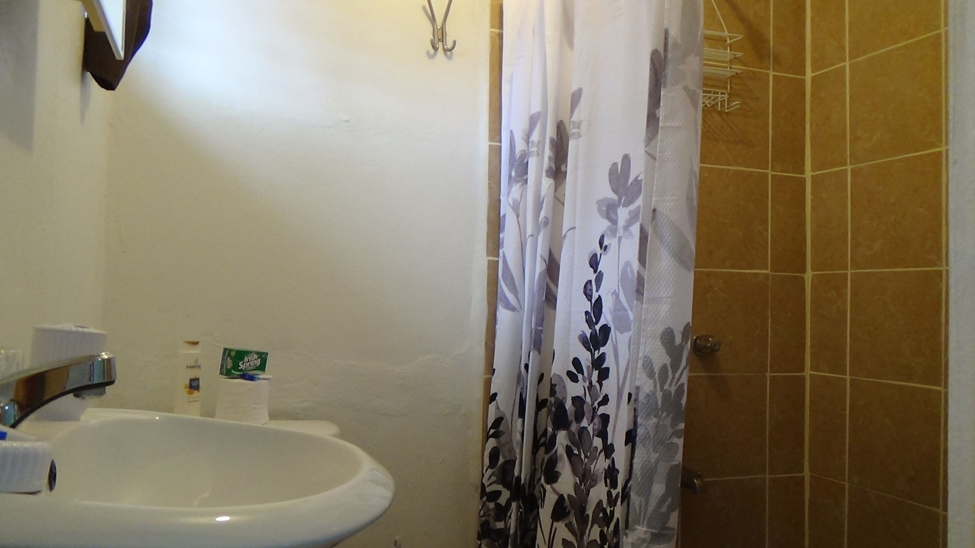 Un baño con un lavabo blanco, un inodoro y una cortina de ducha con estampado floral.