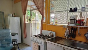 Une cuisine compacte équipée d’une cuisinière à gaz, d’un réfrigérateur et d’un distributeur d’eau.