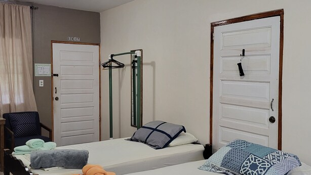 Une chambre d’hôtel avec deux lits, une chaise, un miroir et une porte portant l’inscription « SORTIE ».