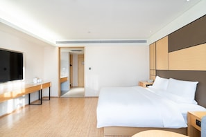 A modern hotel room with a large bed, bedside tables, a flat-screen TV, and a walk-in closet. - JI Hotel Guangzhou Tianhe East Railway Station (Guangzhou)
