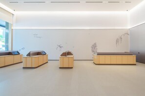 A modern, minimalist room with three wooden reception desks and a plain wall with subtle artwork. - JI Hotel Guangzhou Tianhe East Railway Station (Guangzhou)