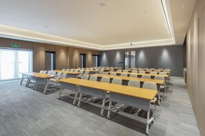 A conference room with rows of tables and chairs, a modern ceiling design, and a large window on the left. - JI Hotel Guangzhou Tianhe East Railway Station (Guangzhou)
