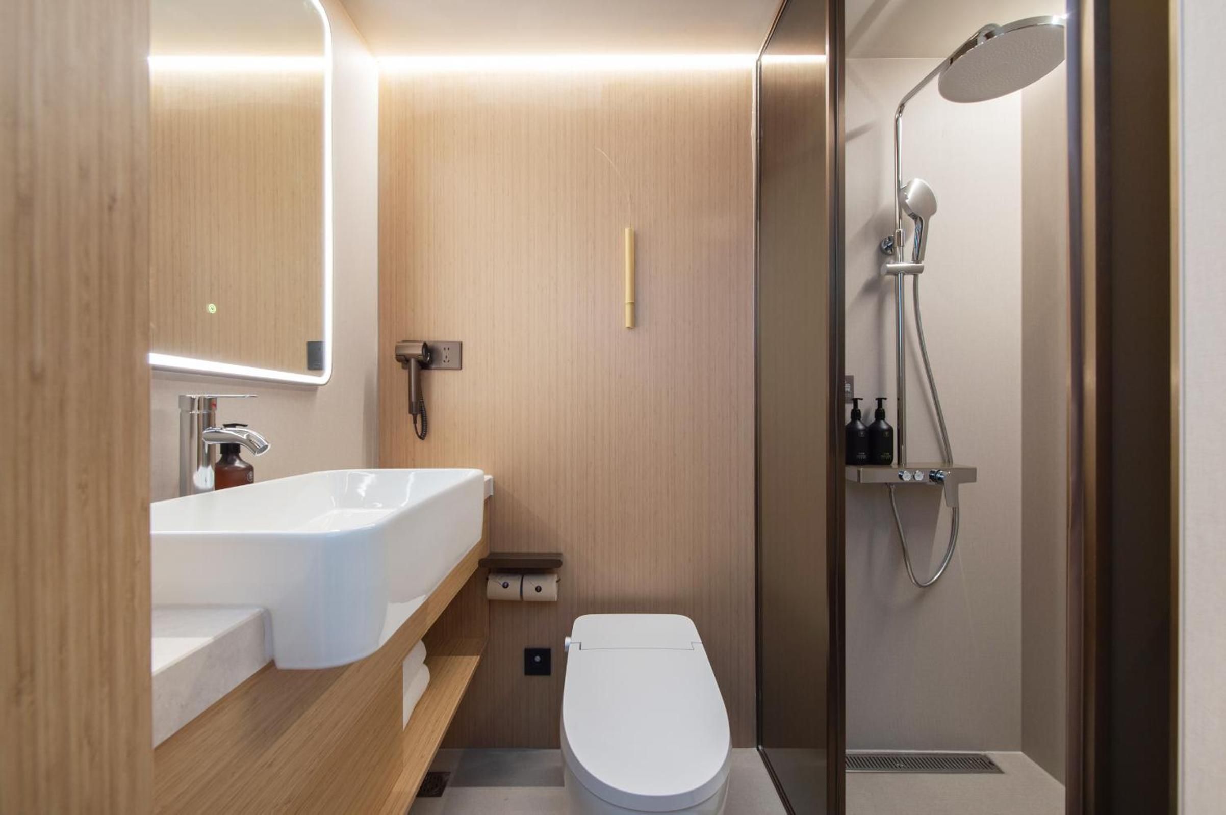 A modern bathroom with a white sink, toilet, and shower.
