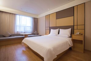 A modern hotel room with a large bed, a seating area with a table, and a bedside telephone. - JI Hotel Guangzhou Tianhe East Railway Station (Guangzhou)