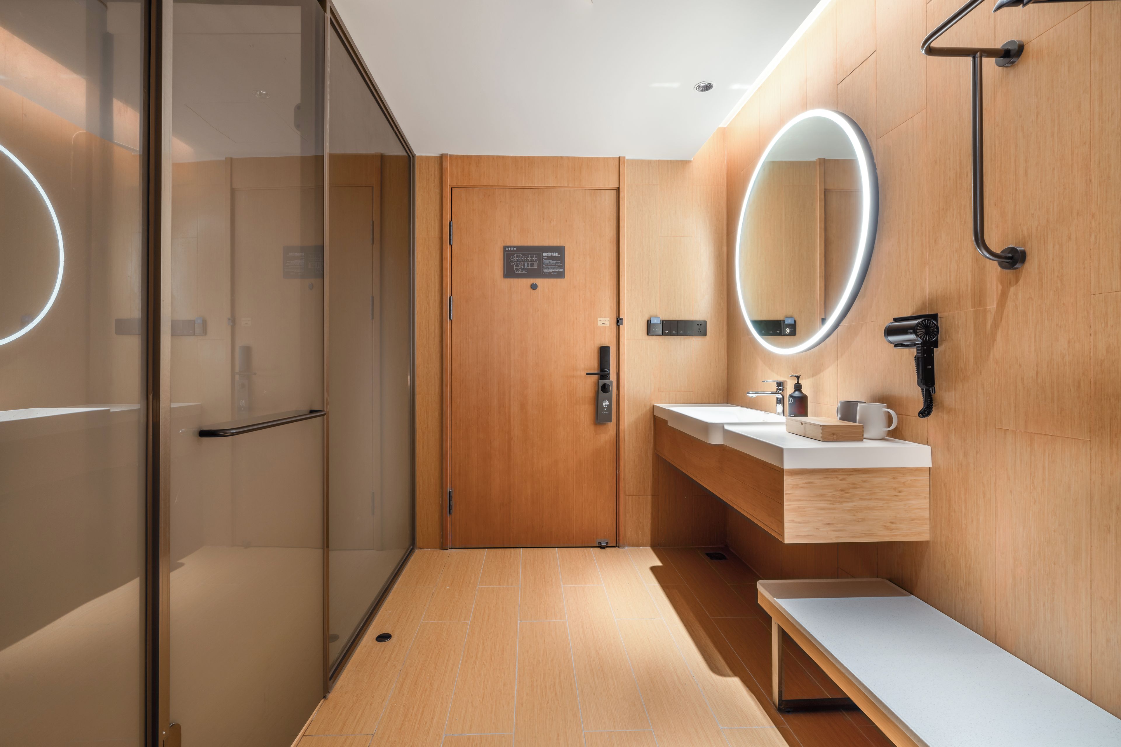 A modern bathroom with a glass shower enclosure, a wooden vanity with a mirror, and a bench.
