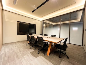 A conference room with a long table, black chairs, a flat-screen TV, and glass walls. - JI Hotel Guangzhou Tianhe East Railway Station (Guangzhou)