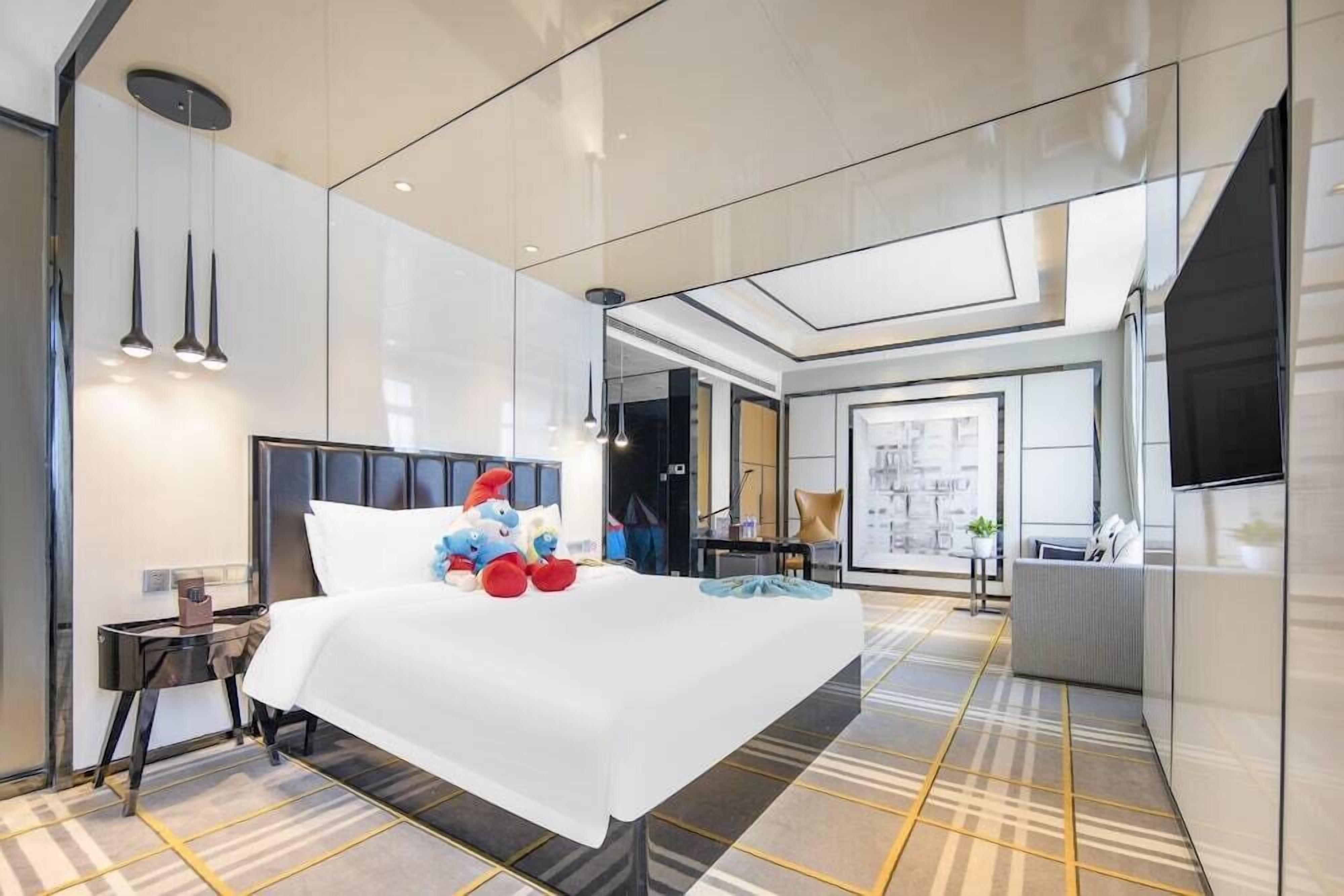 A modern hotel room with a large bed, a desk, and a seating area.