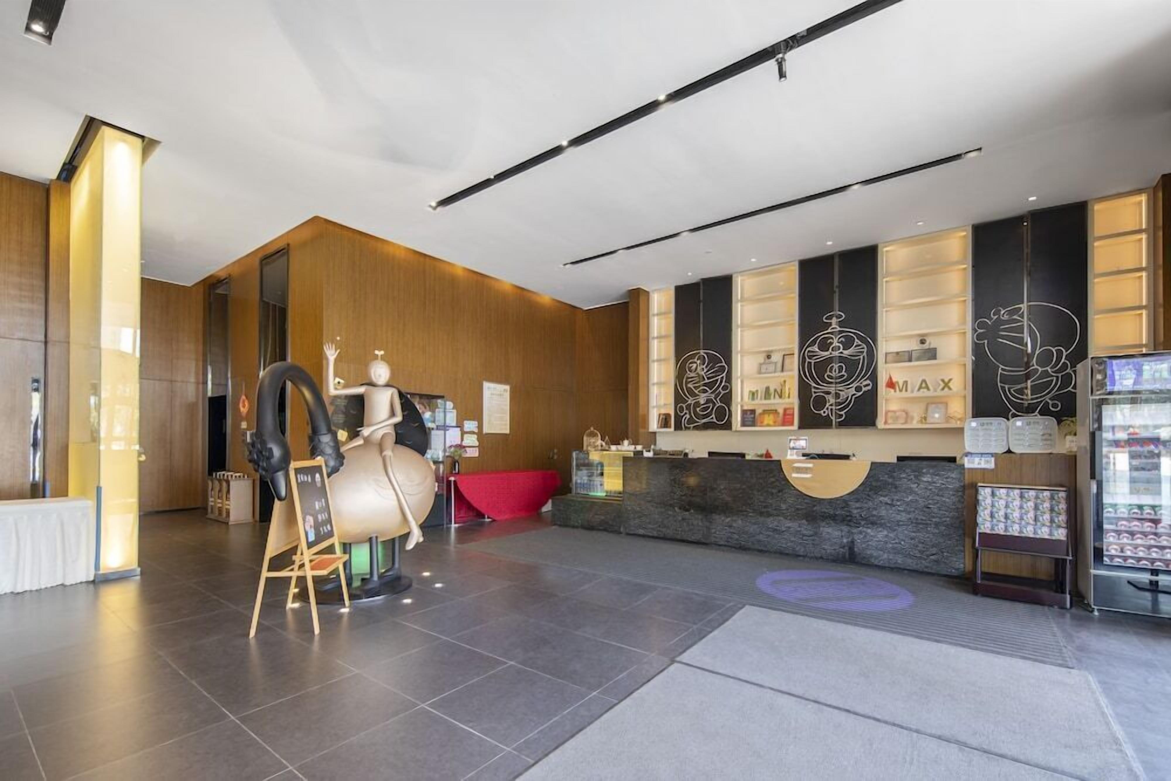 Eine moderne Hotelhalle mit einer Rezeption, einer großen Skulptur und einem Automaten.