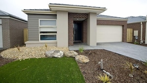 A modern single-story house with a garage, a front porch, and a well-maintained lawn. - Villa Mystic (POINT COOK)