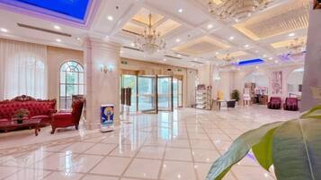 A spacious lobby with a marble floor, a red sofa, and a chandelier.