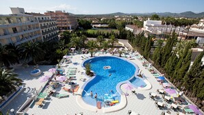 Une grande piscine extérieure dotée de plusieurs espaces de détente et bordée de palmiers.