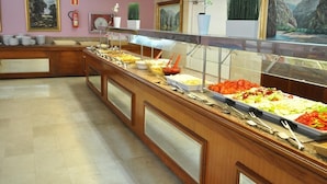A buffet with various food items, a wooden counter, and framed paintings on the wall. - Hostal BEI Juan Mallorca (Sant Llorenc des Cardassar)