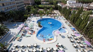 Une grande piscine à la forme originale, entourée de chaises longues et de parasols.