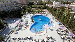 A large outdoor swimming pool with multiple lounge areas and palm trees. - Hostal BEI Juan Mallorca (Sant Llorenc des Cardassar)