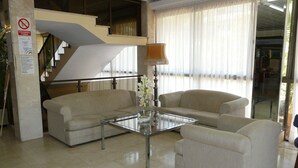 Un salon moderne avec une table basse en verre, deux canapés et une lampe.