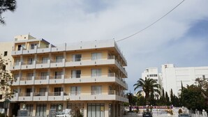 A multi-story hotel with balconies, a signboard, and palm trees in the background. - Hostal BEI Juan Mallorca (Sant Llorenc des Cardassar)