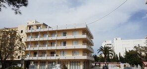 Ein mehrstöckiges Hotel mit Balkonen, einer Schautafel und Palmen im Hintergrund.