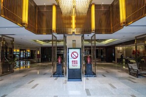 Een hotel lobby met een modern design, met een centraal receptiebalie, een kroonluchter en een bordje dat roken verbiedt.