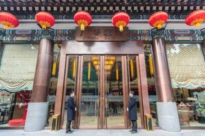Een traditioneel Chinees gebouw met een bord, grote glazen deuren en rode lantaarns.