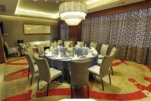 A round dining table with chairs, a chandelier, and a patterned wall in a hotel room. - Chongqing Plaza Hotel (Chongqing)