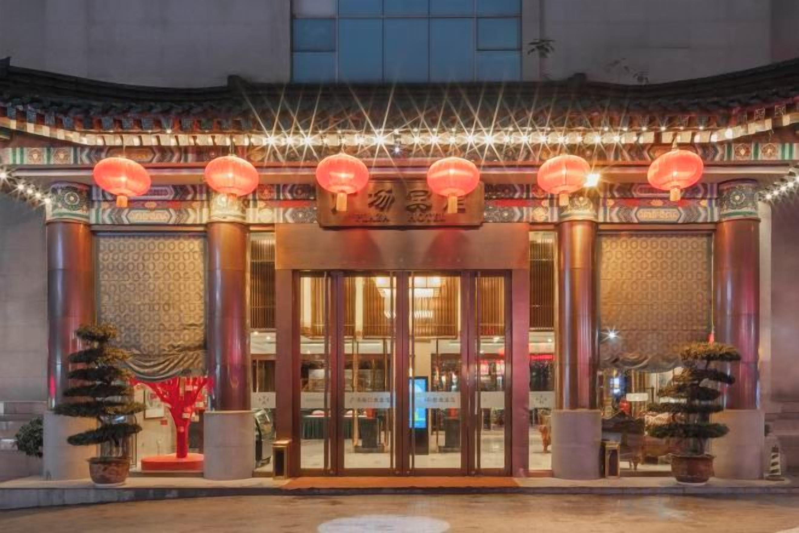 A traditional building entrance with a sign, lanterns, and potted plants.