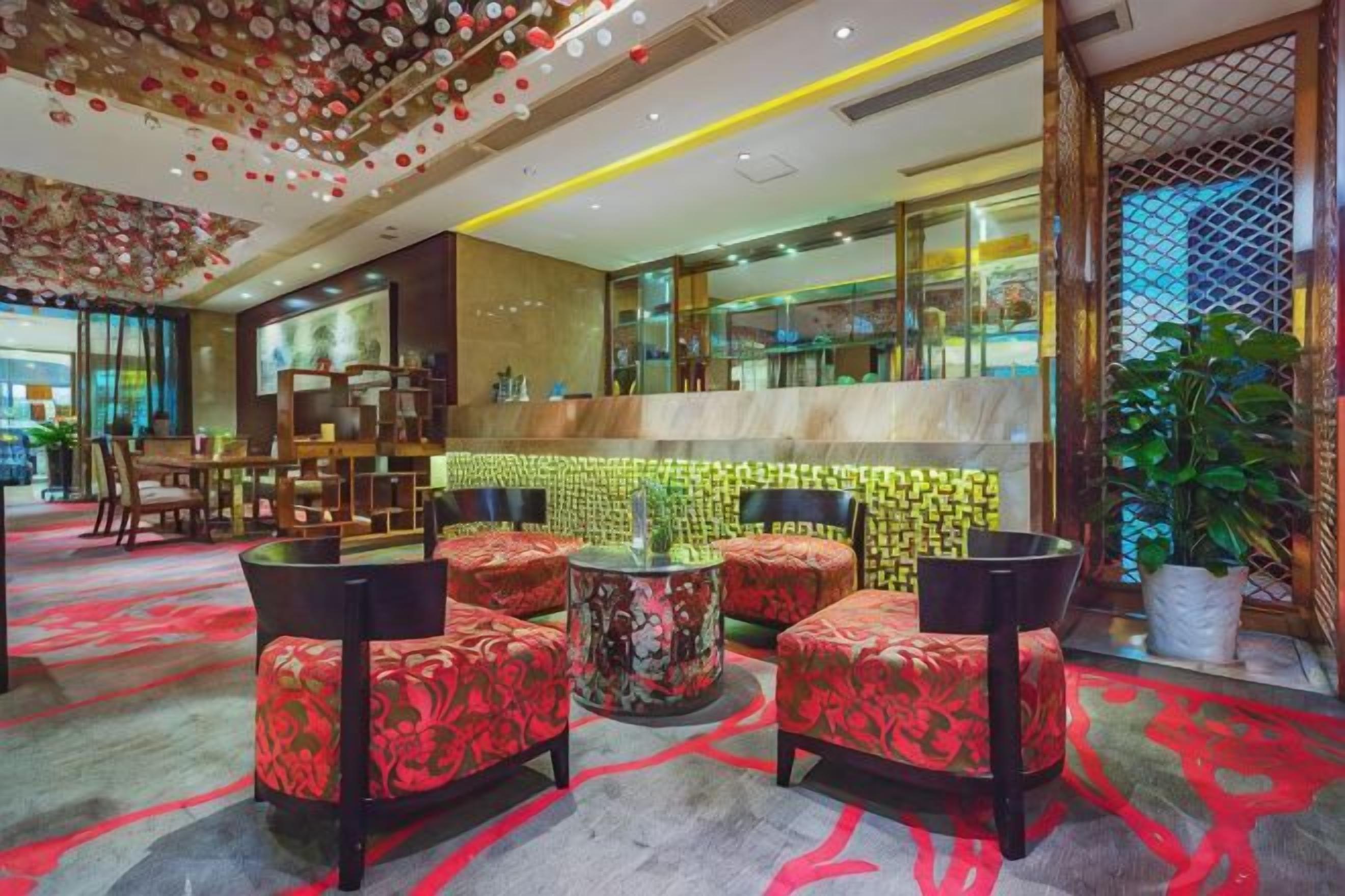 A hotel lobby with a bar area, seating with patterned upholstery, and a decorative ceiling.