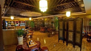 A traditional interior with wooden floors, a reception desk, seating areas, and decorative plants.