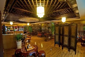 A traditional interior with wooden floors, a reception desk, seating areas, and decorative plants. - Chongqing Plaza Hotel (Chongqing)