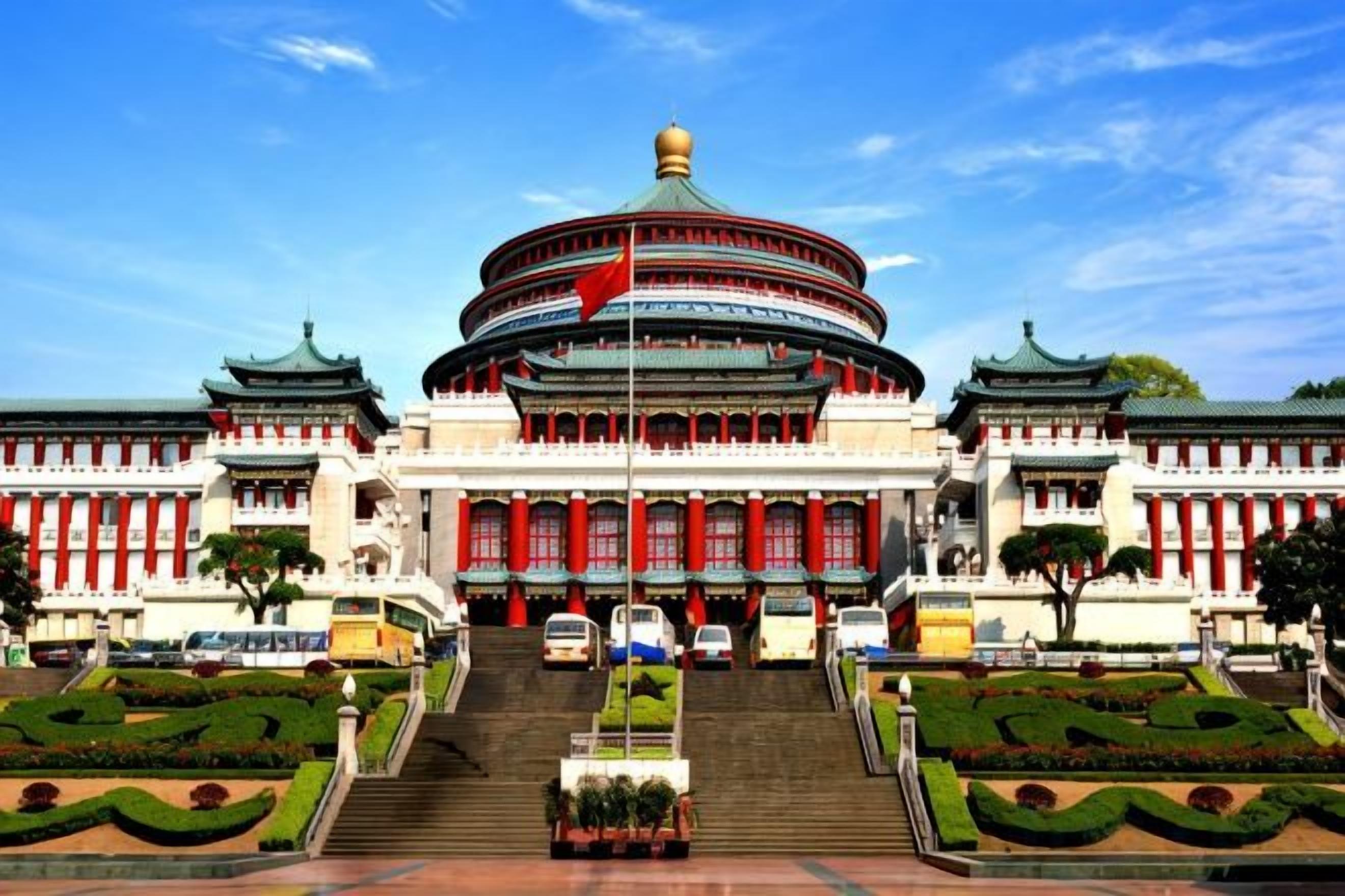 A large, traditional building with a circular central structure, wide steps leading up to it, and symmetrical gardens in front.