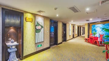 A hotel corridor with a reception desk, a fountain, and a mural on the wall.