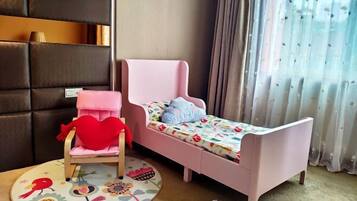 A child's bedroom with a pink bed, a chair with a heart-shaped cushion, and a colorful rug.