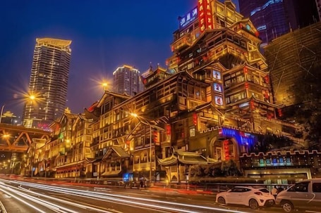 A traditional building with multiple stories, illuminated by artificial lighting, and surrounded by modern high-rise buildings.. Chongqing Plaza Hotel