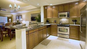 A modern kitchen with wooden cabinets, stainless steel appliances, and a central island. - Reunion Resort - 3 BR Condo, Ground Floor, Patio - JHH 45890 (Kissimmee)