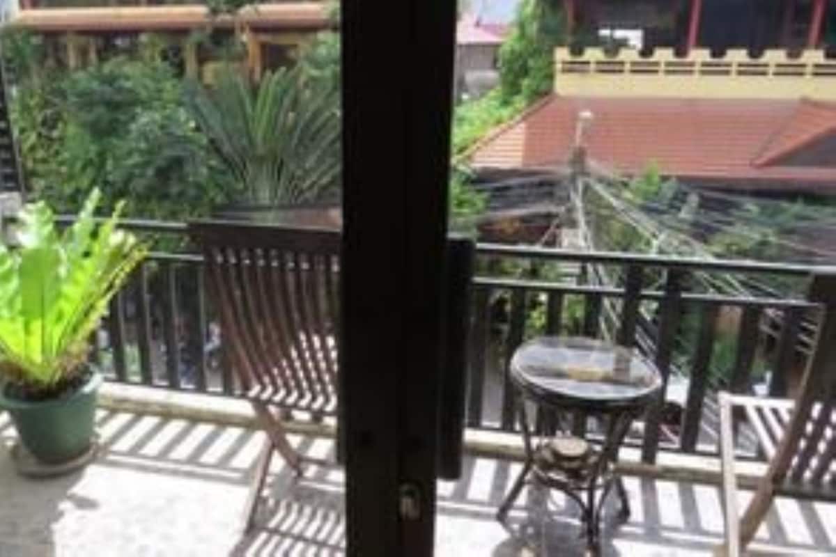 A balcony with a potted plant, a small table, and a chair.
