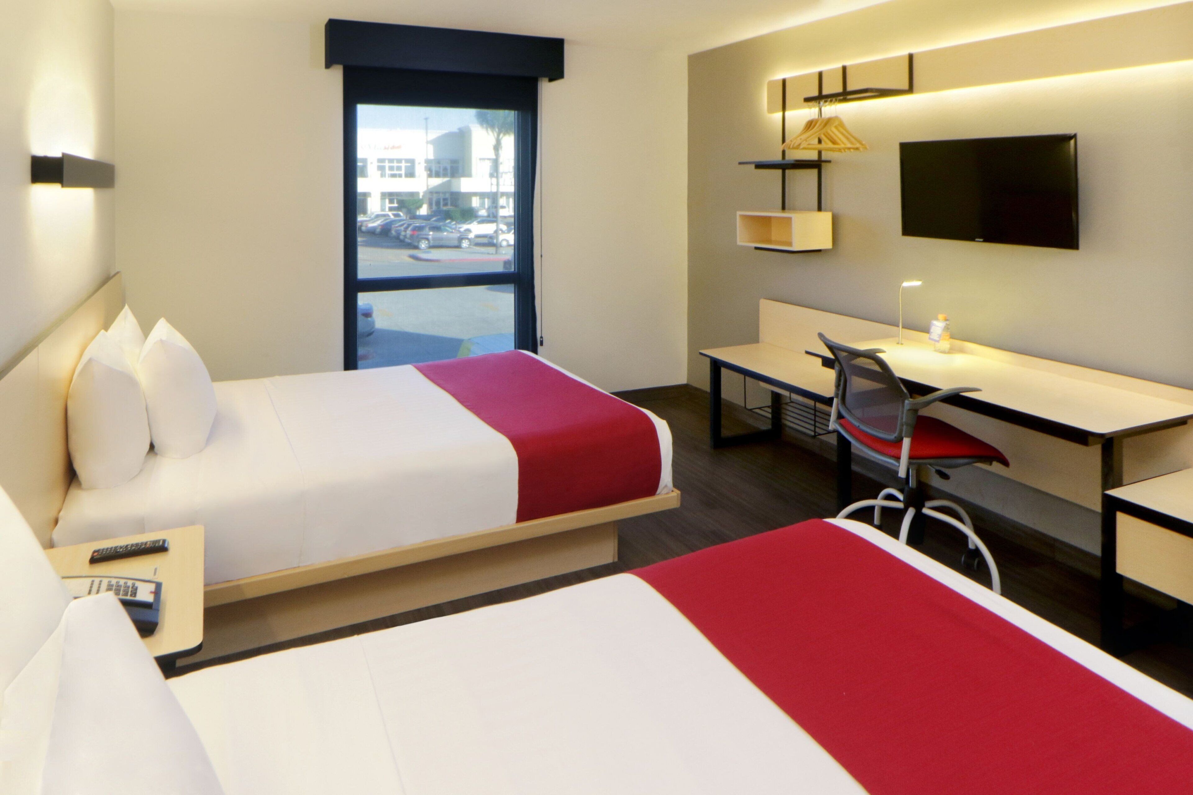 A hotel room with a bed, a desk, a chair, a TV, and a window.