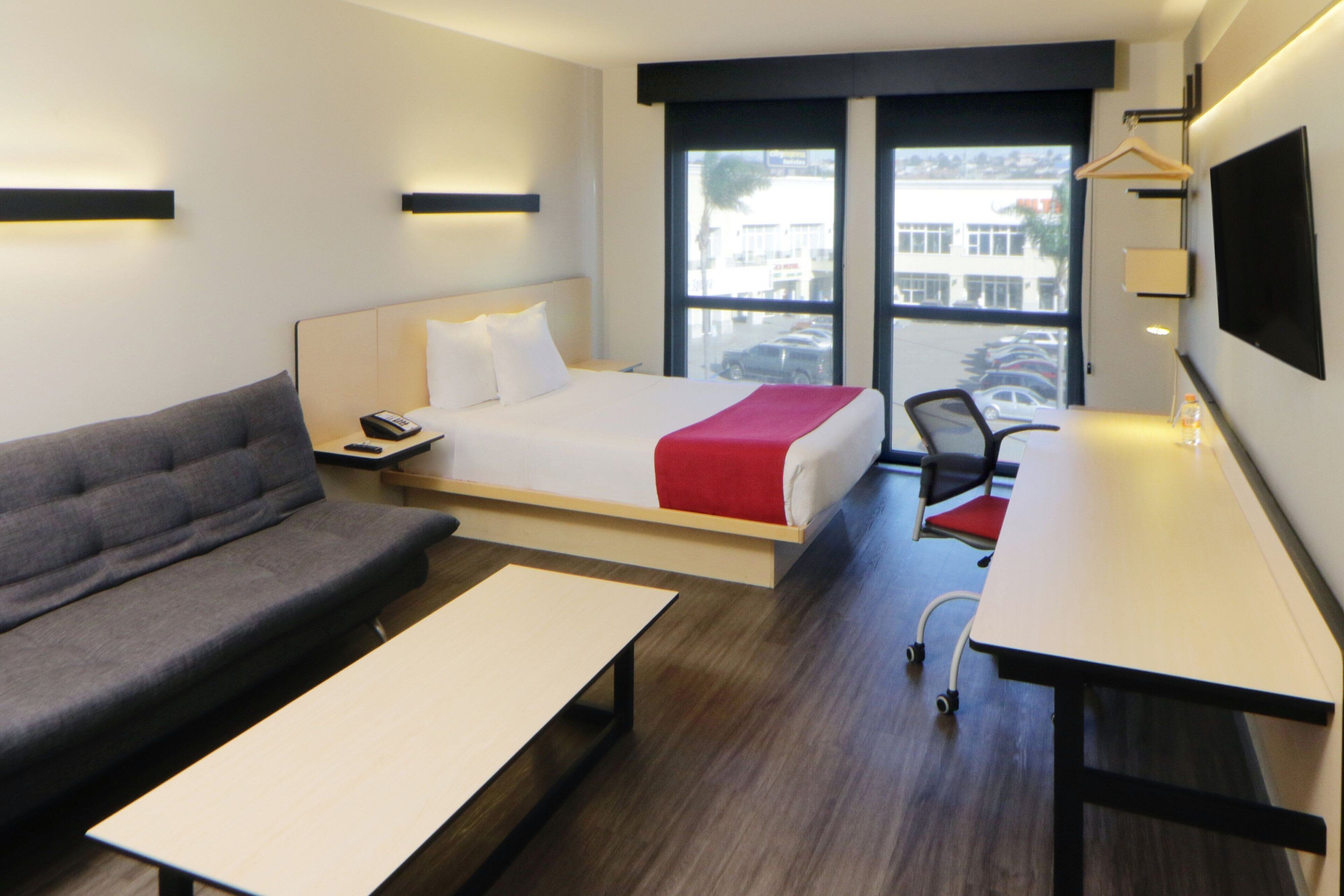 Et hotelværelse med en seng, en sofa, et skrivebord og et fjernsyn.