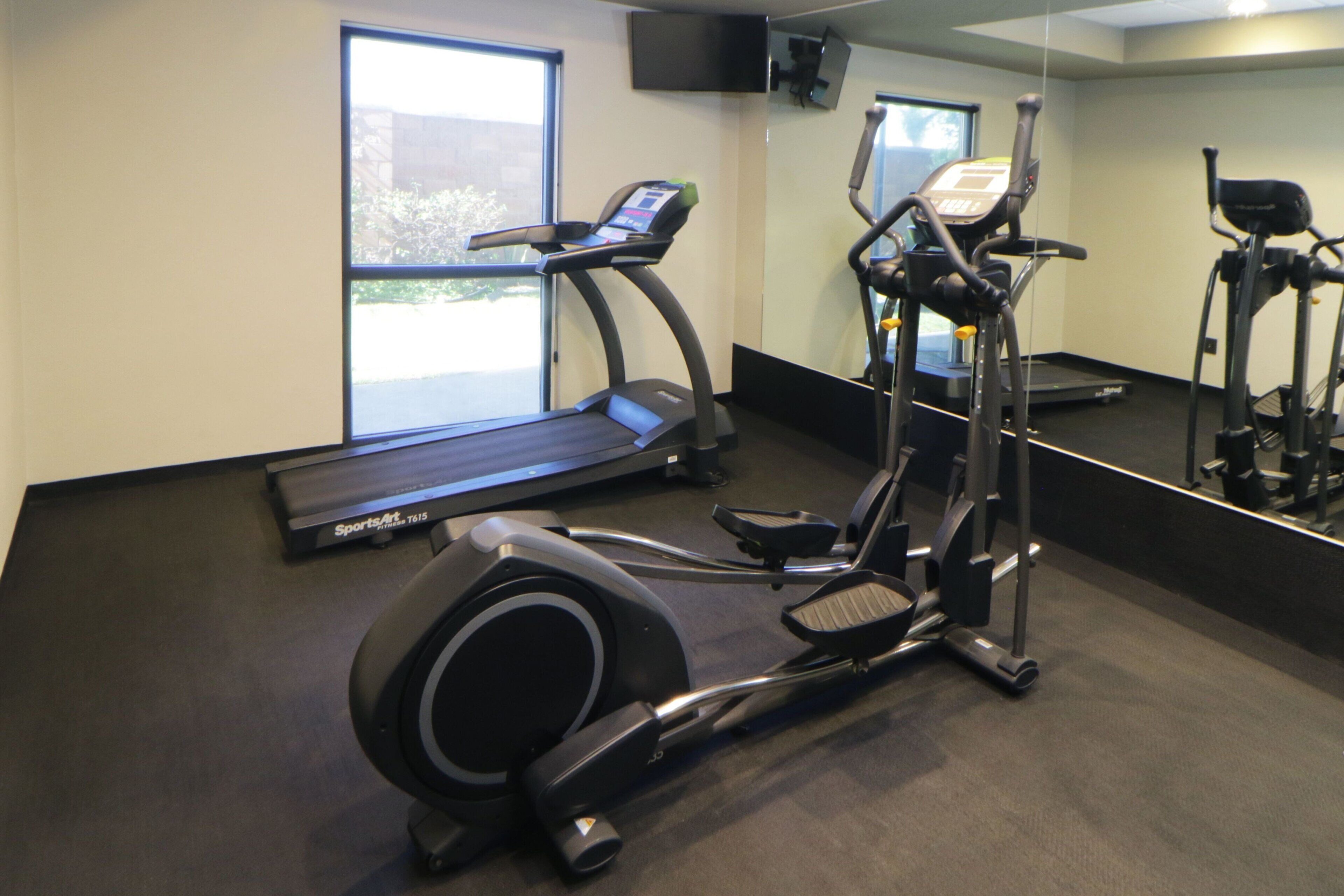 Un gimnasio con cinta de correr, elíptica y bicicleta estática.