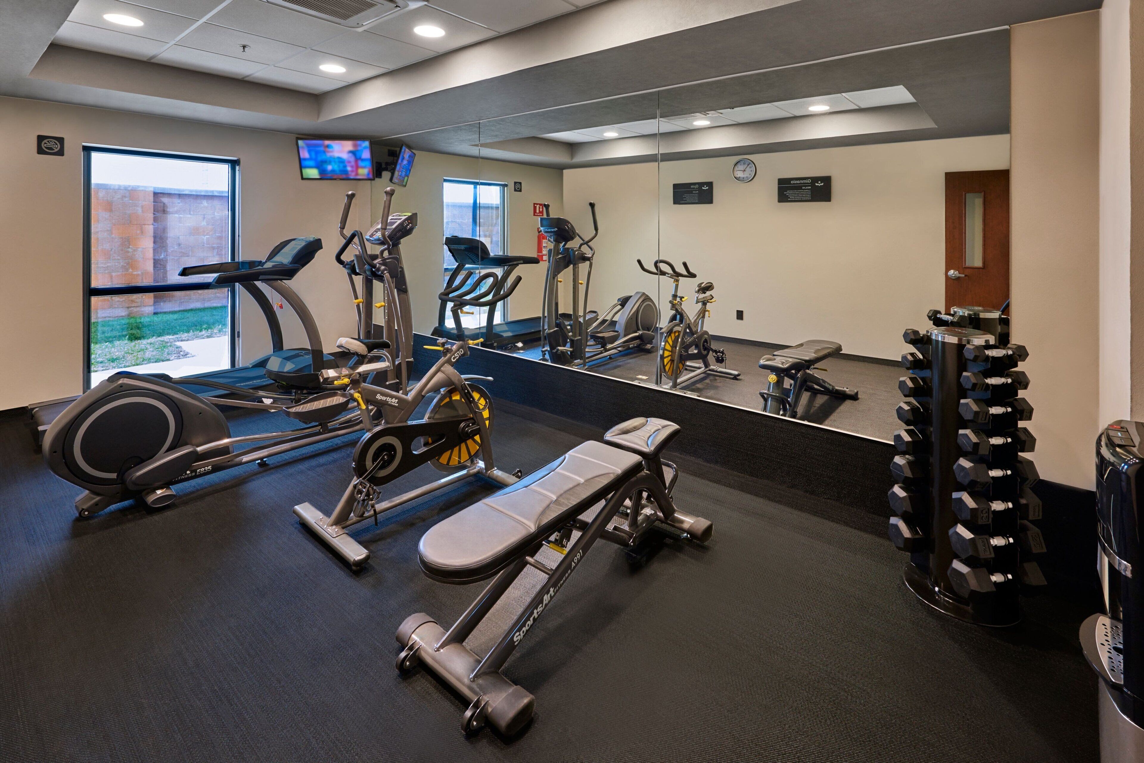 Une salle de sport équipée de divers appareils d’exercice, notamment des tapis de course, des vélos d’appartement et des poids libres.