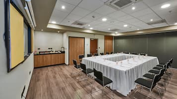 A conference room with a long table, black chairs, and a projector screen.