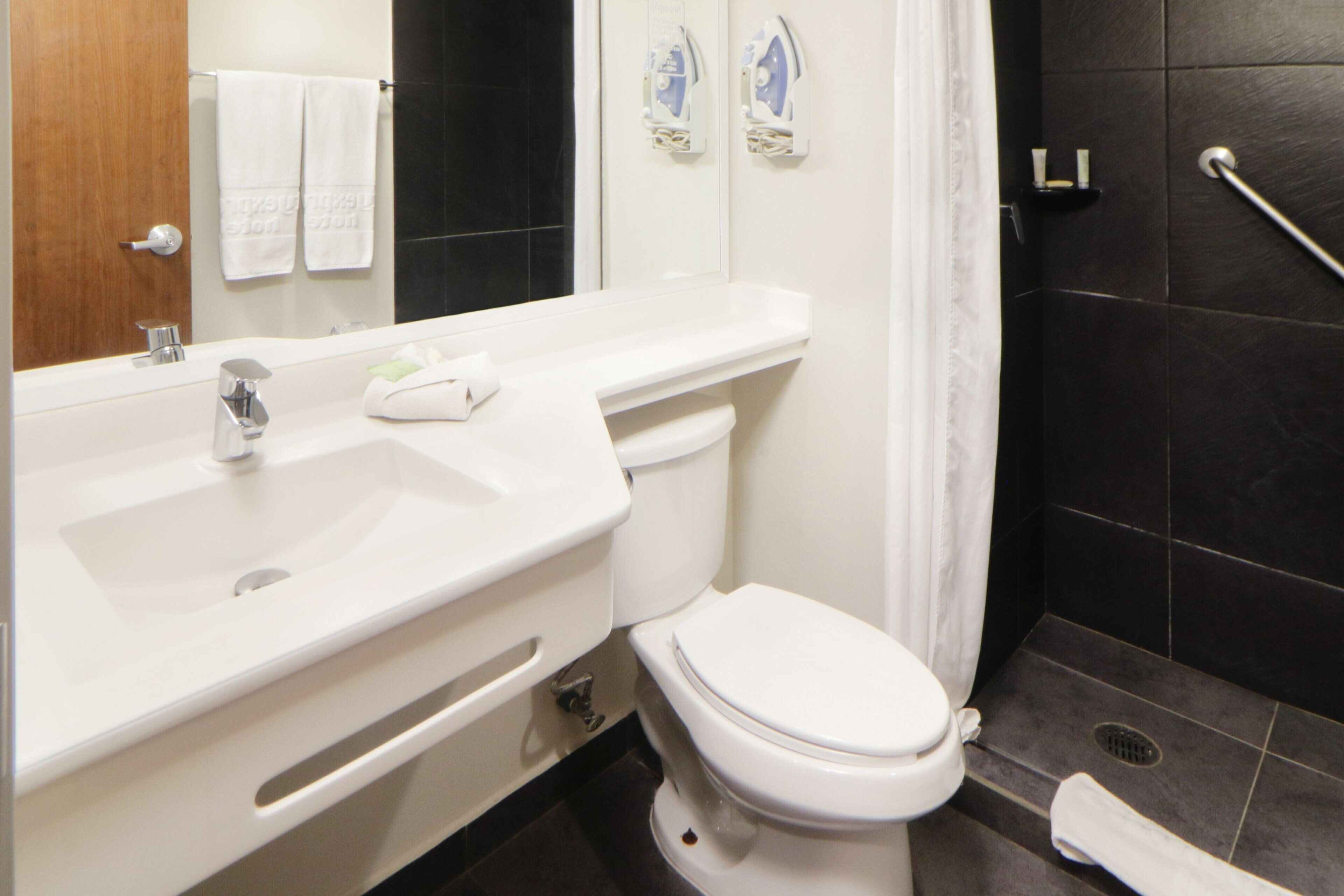 A modern bathroom with a white sink, toilet, and shower area.