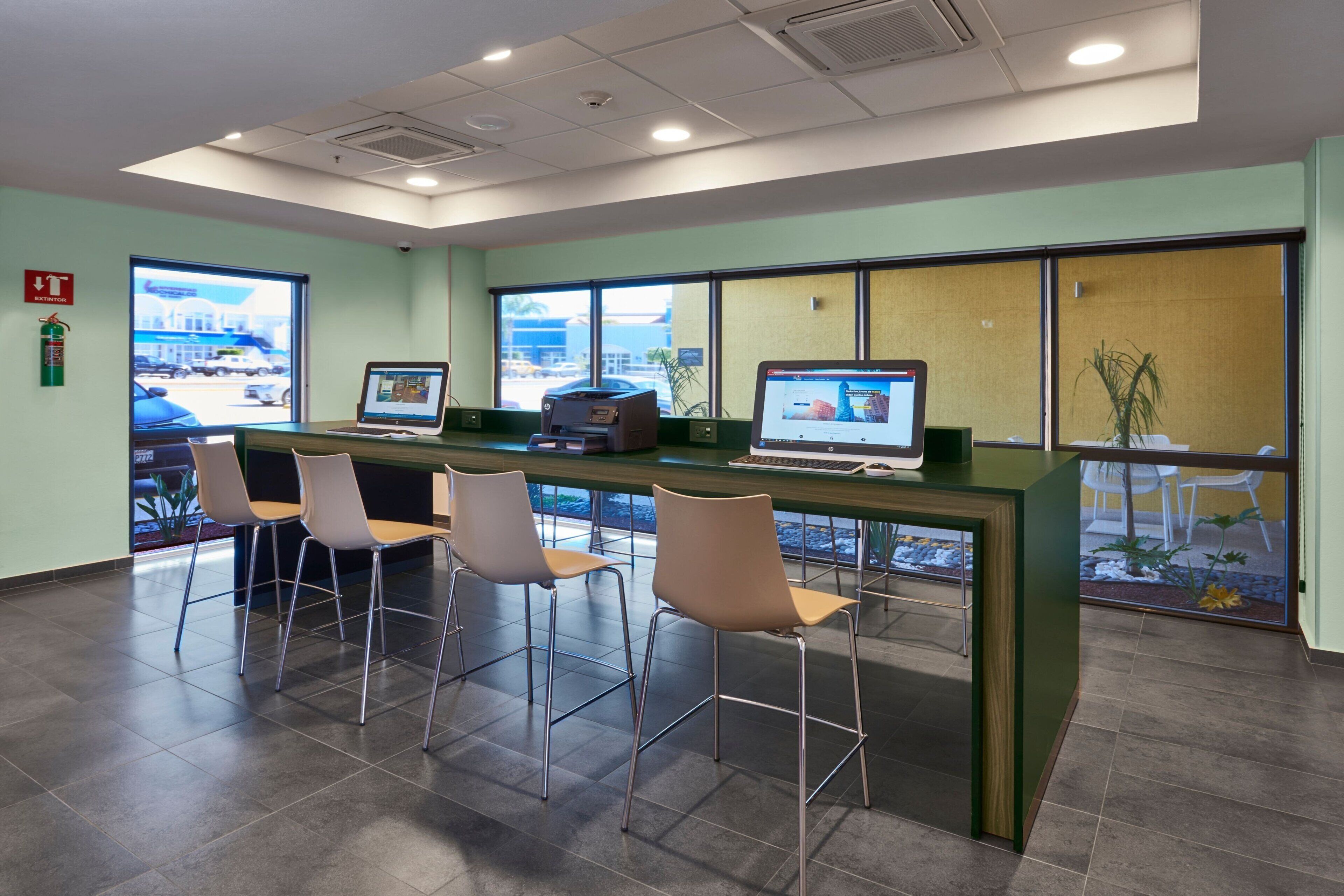 A reception area with a counter, computers, and four chairs.