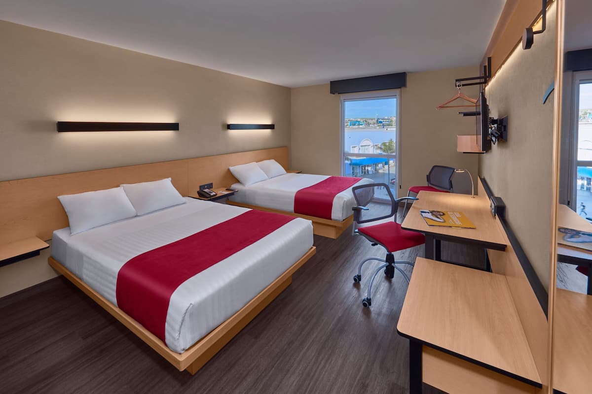 A hotel room with two beds, a desk, and a chair.